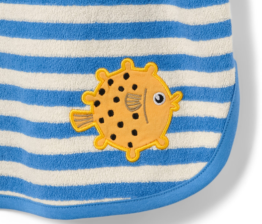 Gros plan sur un poncho en tissu éponge pour enfant avec des rayures bleues et blanches et un motif de poisson jaune.