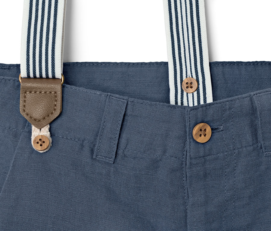 Gros plan d'un short bleu pour enfant avec des boutons et des bretelles rayées.