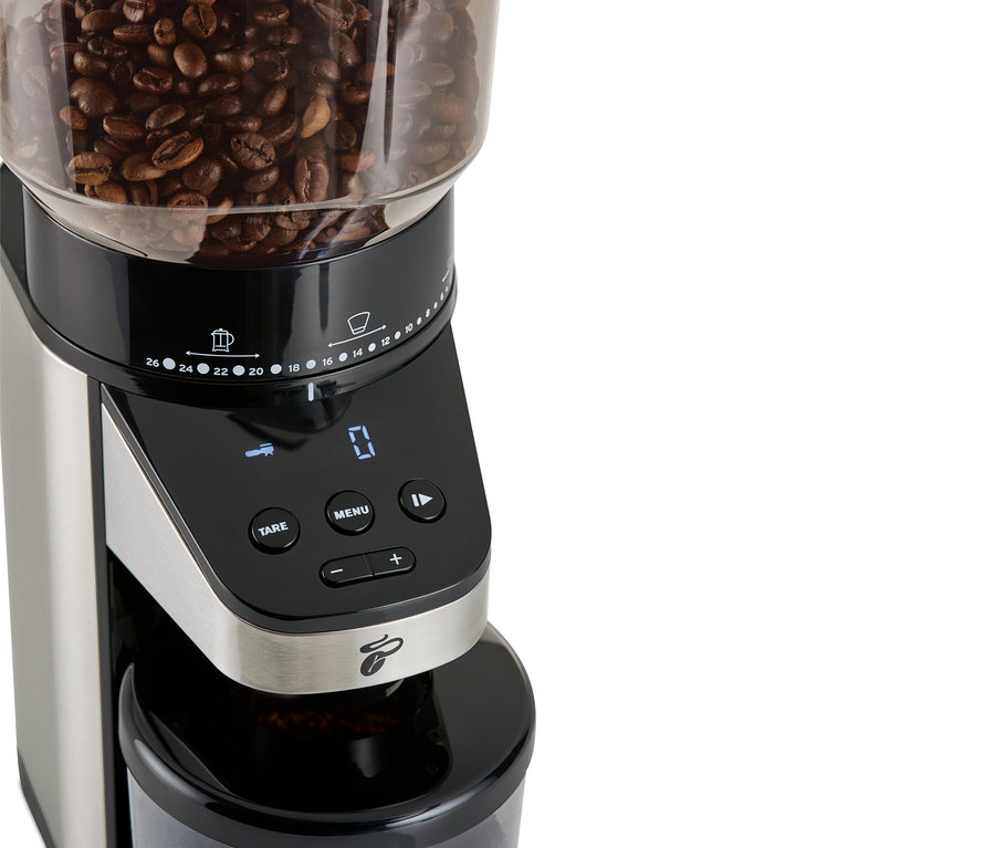 Gros plan d'un moulin à café électrique avec balance, avec des grains de café sur le dessus.