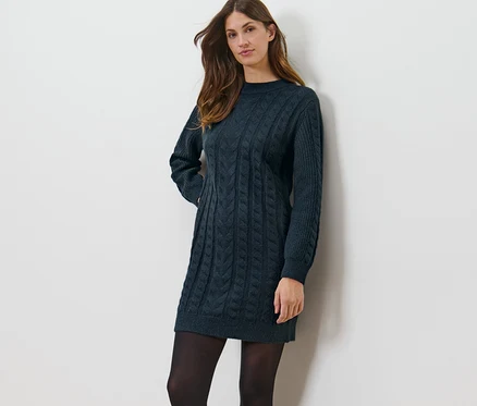 Femme posant dans une robe en tricot avec motif torsadé.