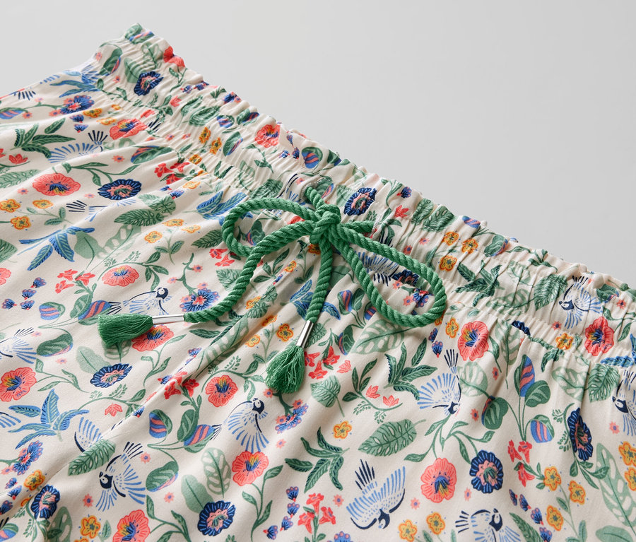 Gros plan sur un ensemble pyjama shorty à motif floral avec un cordon de serrage vert.