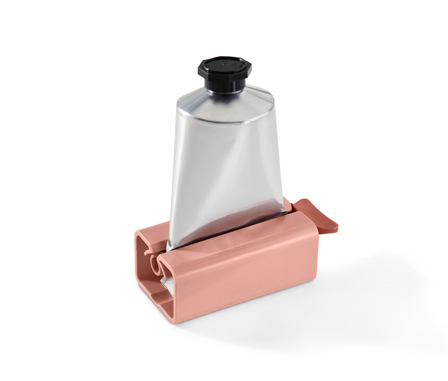 Un tube argenté dans un presse-tube rose.