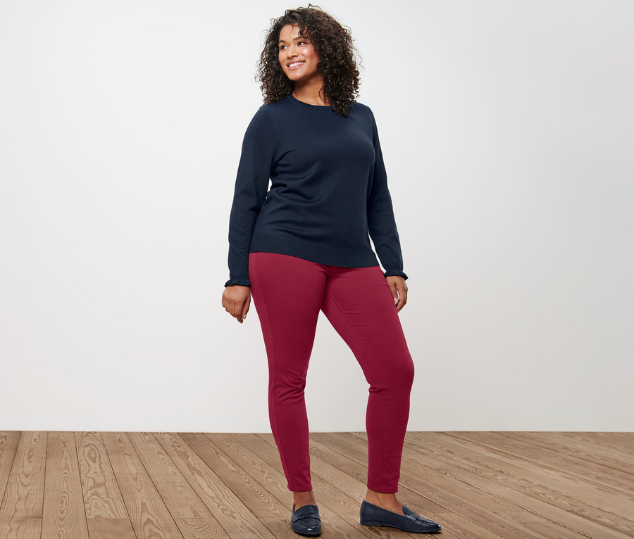 Femme posant en pull en maille fine bleu foncé avec poignets ruchés et jegging.