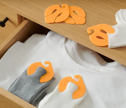 Dans un tiroir, un t-shirt blanc et des chaussettes appariées avec 20 clips à chaussettes.