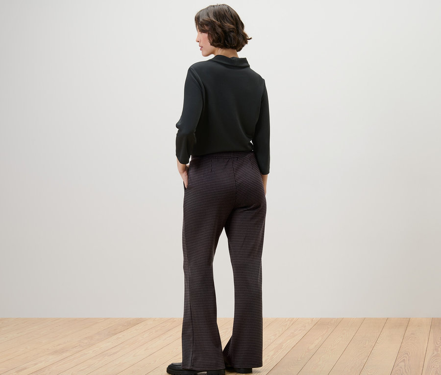 Une femme, vue de dos, porte un pantalon à enfiler noir à jacquard pied-de-poule.