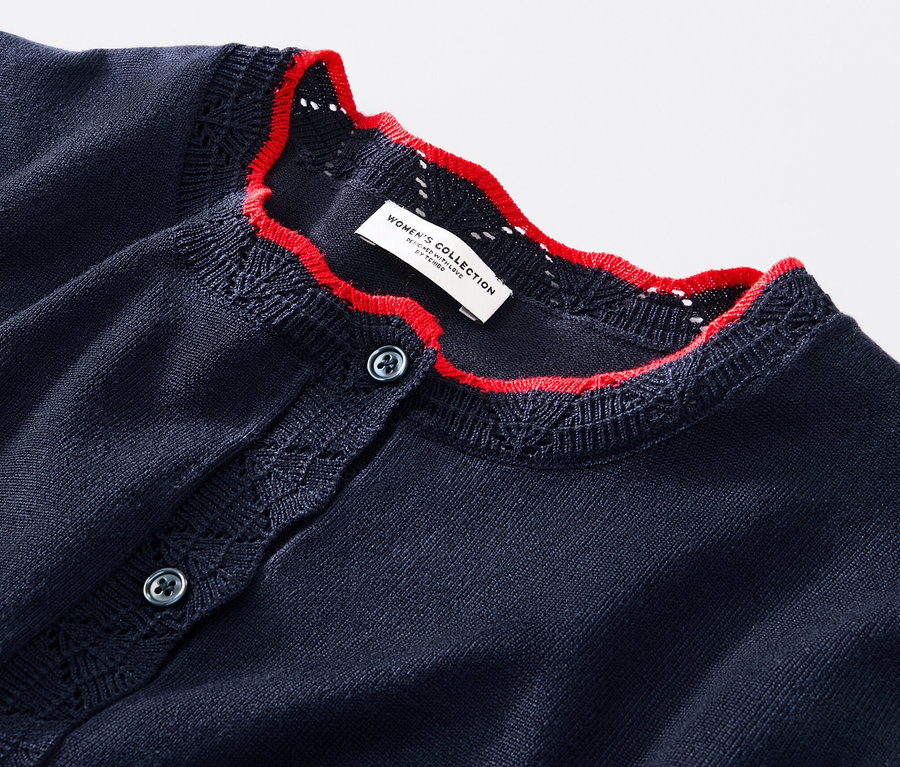 Détail d'un cardigan à maille fine avec bord ondulé.