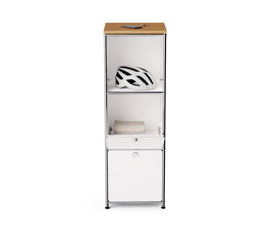 Commode étroite en métal « CN3 » blanche avec plateau en bois et deux abattants. Un casque est visible en haut, une serviette au milieu.