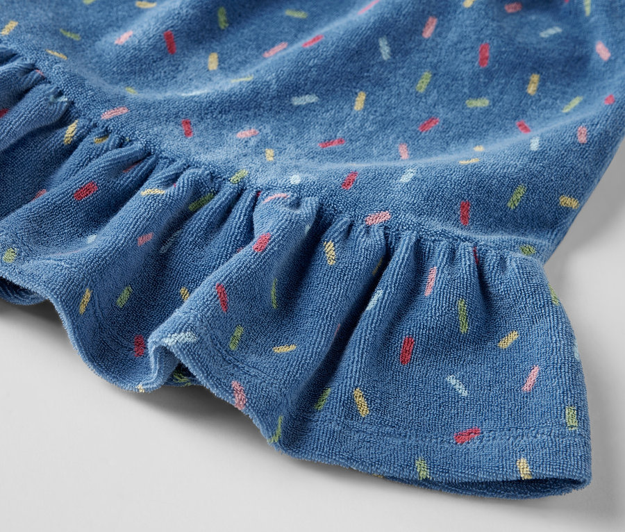 Détail d'une jupe éponge pour enfants avec des volants et un imprimé coloré.