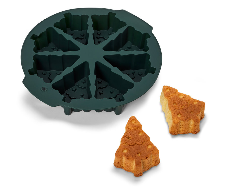 Moule à pâtisserie en silicone vert en forme de sapin de Noël avec deux sapins cuits à côté.
