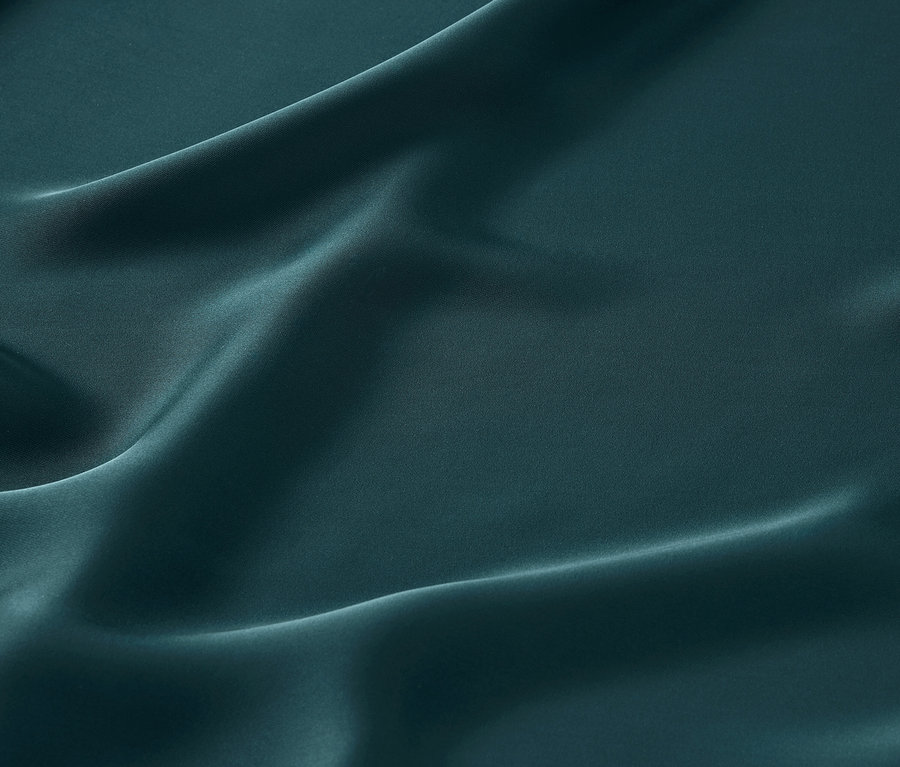 Gros plan d'un tissu en satin vert émeraude avec de délicats plis.