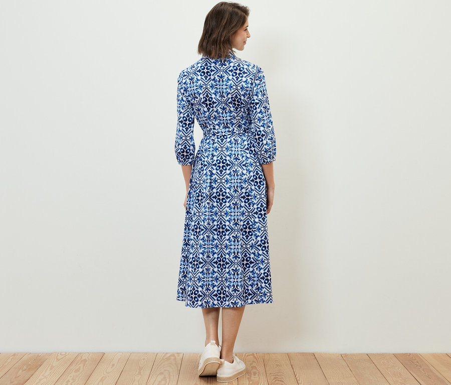 Une femme, vue de dos, porte une robe mi-longue imprimée.