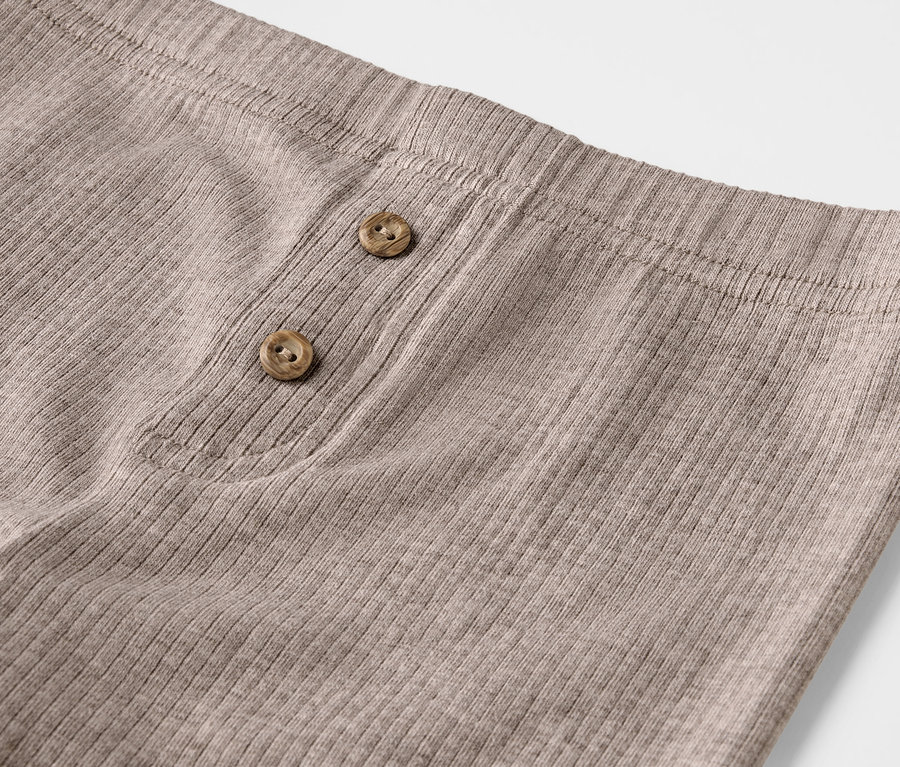 Gros plan de 2 leggings côtelés pour enfants avec boutons décoratifs.