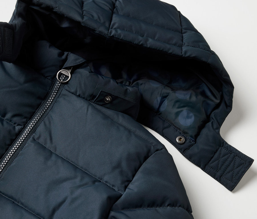 Vue détaillée d'un manteau thermique pour enfants avec capuche et fermeture éclair.