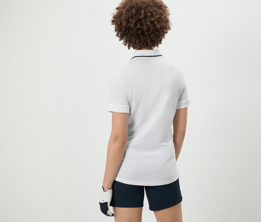 Vue arrière d'une femme aux cheveux bouclés portant un polo technique blanc.