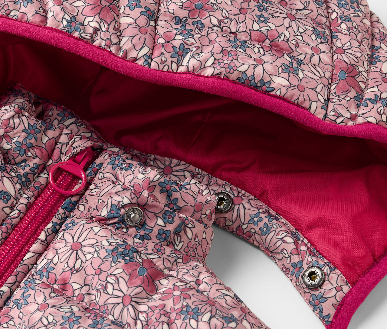 Gros plan sur un anorak matelassé pour enfants à fleurs avec fermeture éclair et boutons-pression.