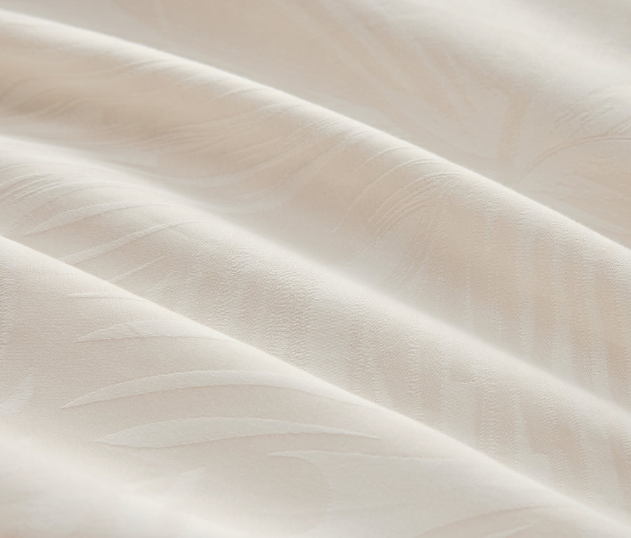 Gros plan d'un tissu crème avec un motif subtil et des plis.