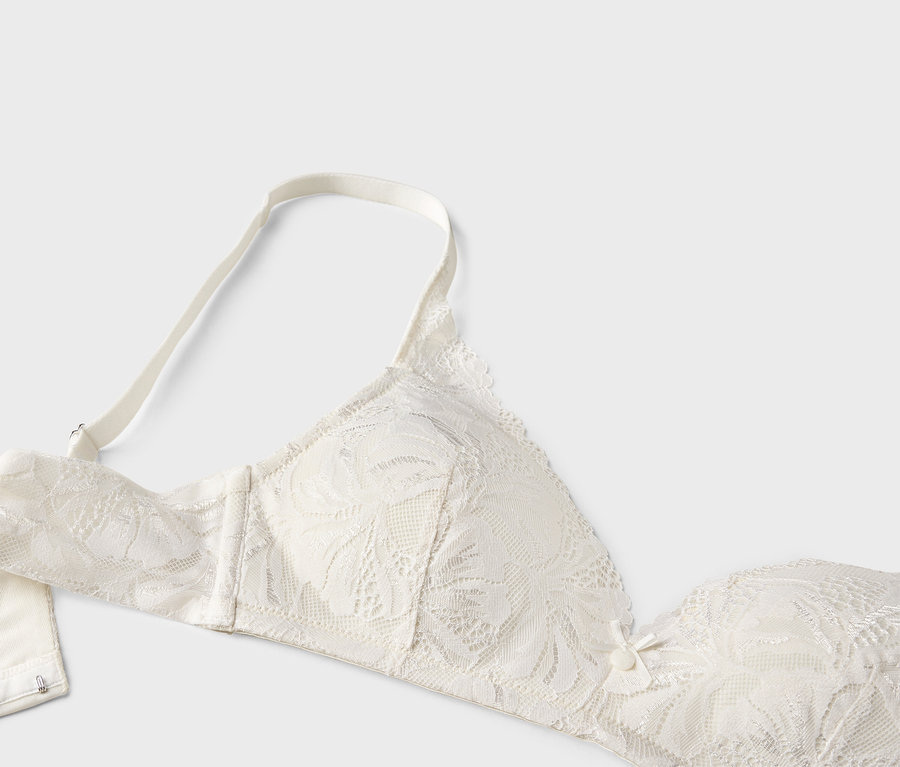 Gros plan d'un soutien-gorge en dentelle blanche avec bretelles sur fond blanc.