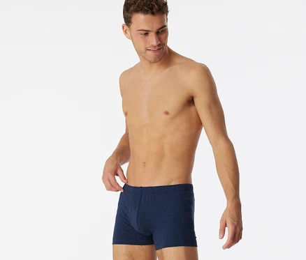 Homme portant un short SCHIESSER bleu marine à imprimé intégral, ajustant la taille.