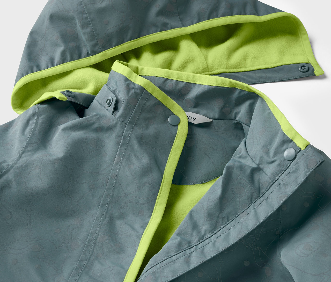 Gros plan sur une veste de pluie thermique pour enfant avec des éléments réfléchissants, veste grise avec doublure et finitions vert lime.