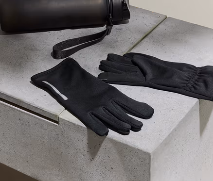 Des gants noirs et une bouteille d'eau reposent sur une surface en béton.