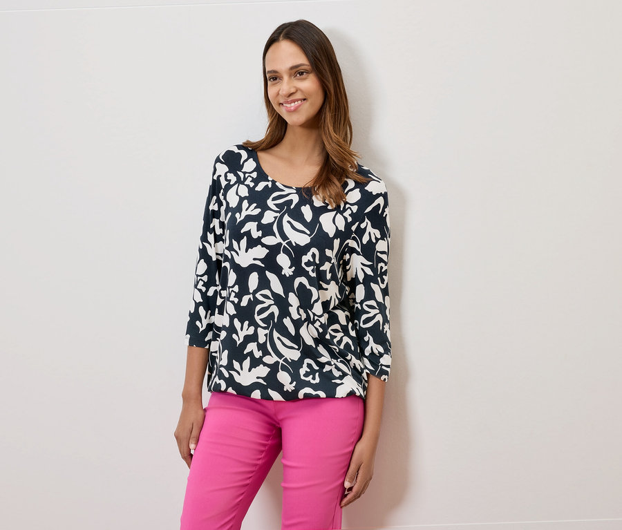 Femme portant un chemisier bleu marine à fleurs et un pantalon rose.