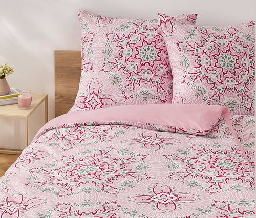 Parure de lit en microfibre rose de taille standard avec un motif floral sur un lit.