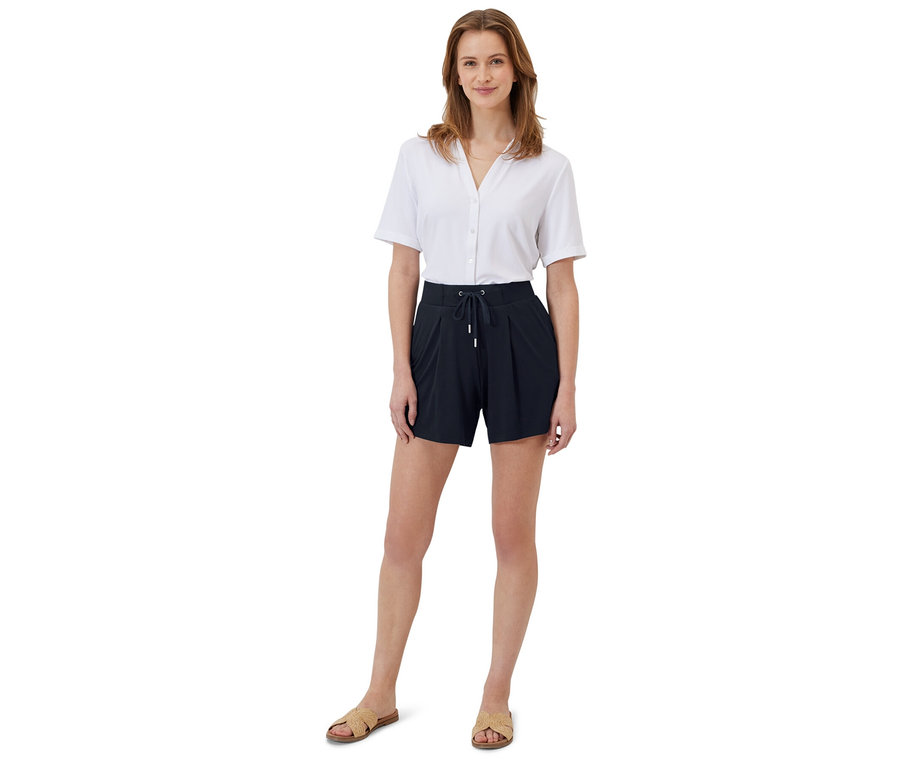 Une femme debout portant une chemise blanche et 2 shorts en jersey.