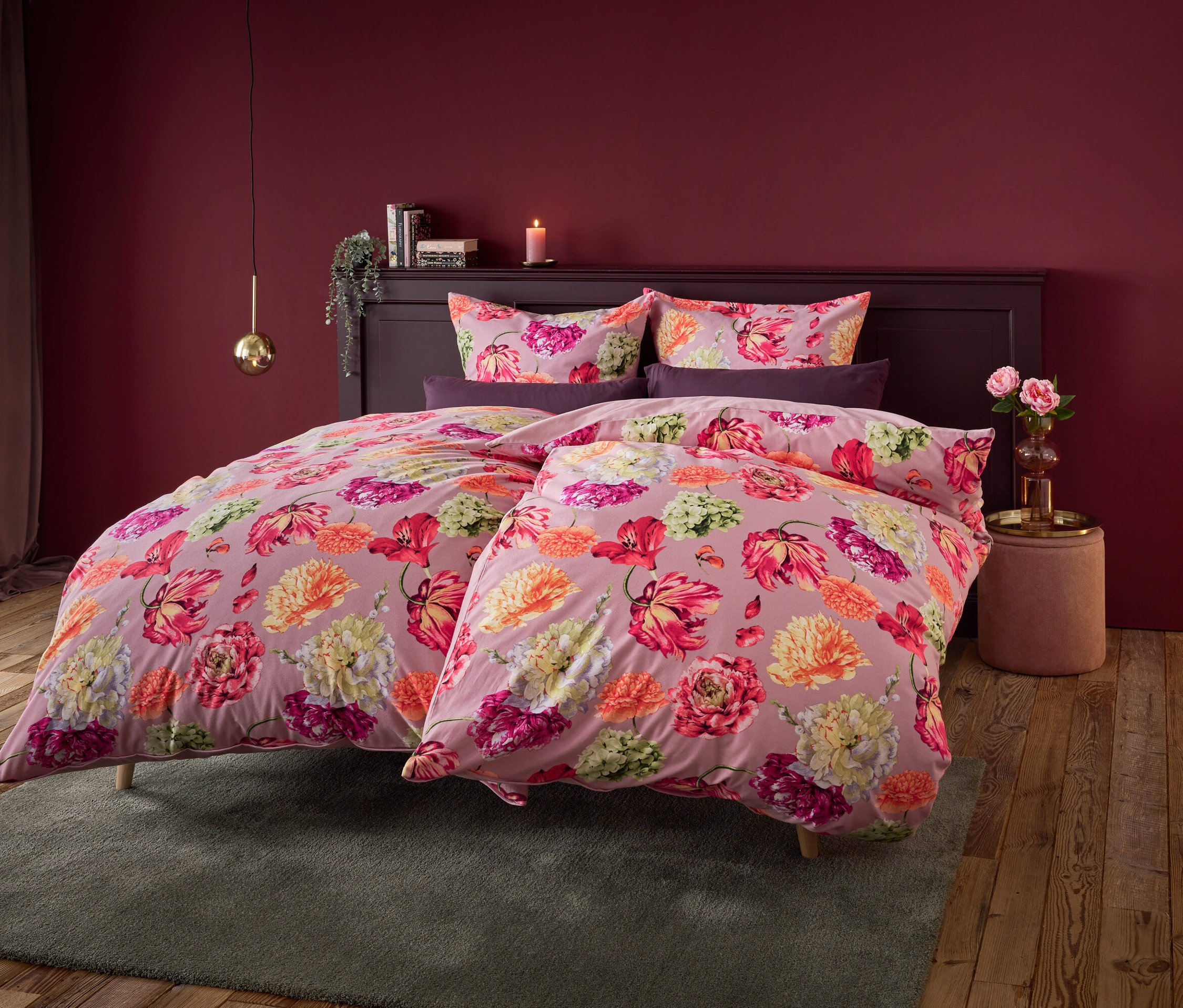 Linge de lit à fleurs sur un lit avec un mur rouge foncé en arrière-plan.