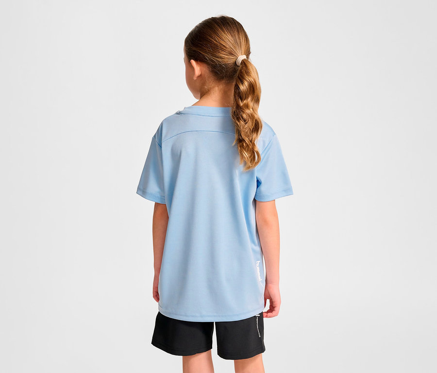 Une fille portant un t-shirt d'entraînement HUMMEL HMLJR pulse bleu clair et un short noir, de dos à la caméra.