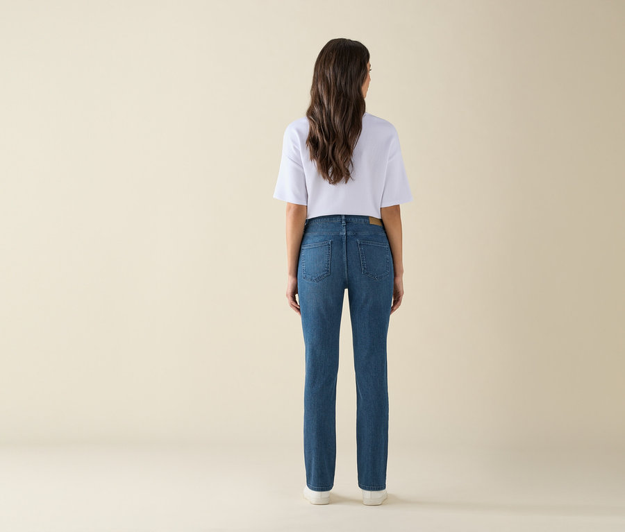 Vue arrière d'une femme portant un jean bleu et un t-shirt blanc.