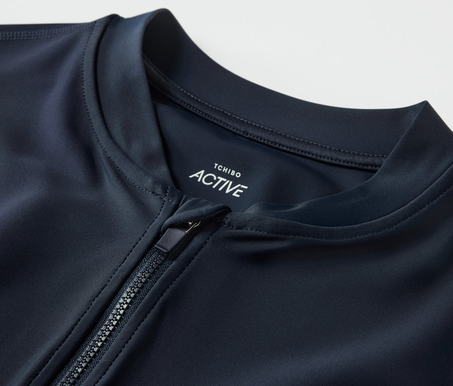 Gros plan sur un t-shirt de sport à protection UV avec une fermeture éclair partiellement ouverte.