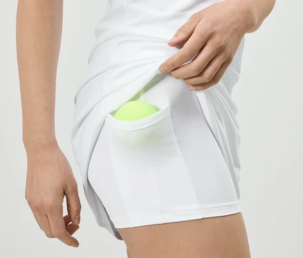 Une femme met une balle de tennis dans la poche d'une robe de sport blanche avec un cycliste.