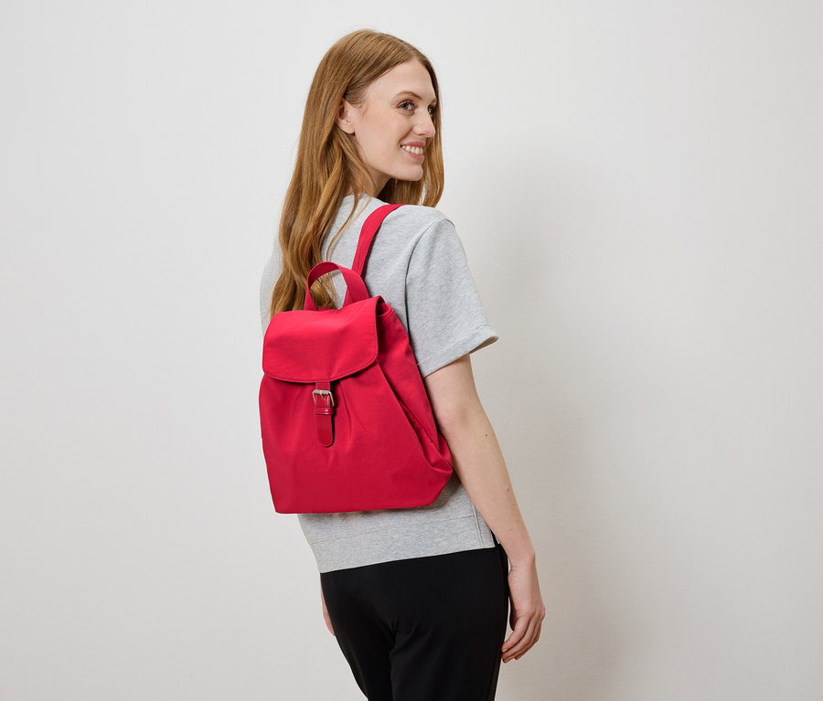 Femme portant un sac à dos rouge regardant vers la gauche.