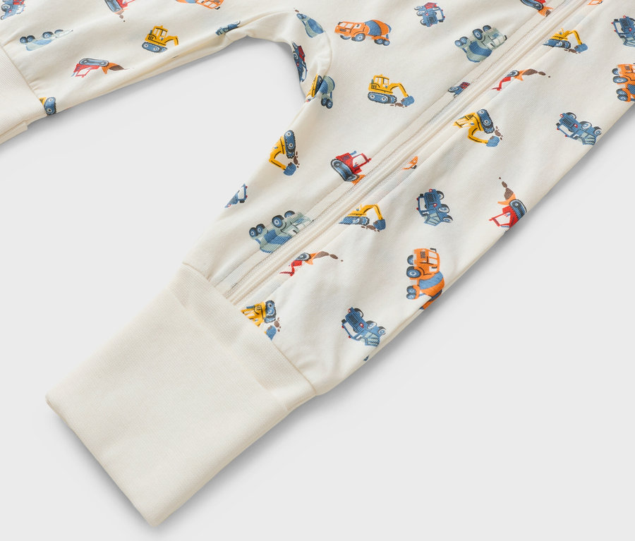 Gros plan sur une grenouillère à manches longues avec fermeture éclair et motif de véhicules de chantier.