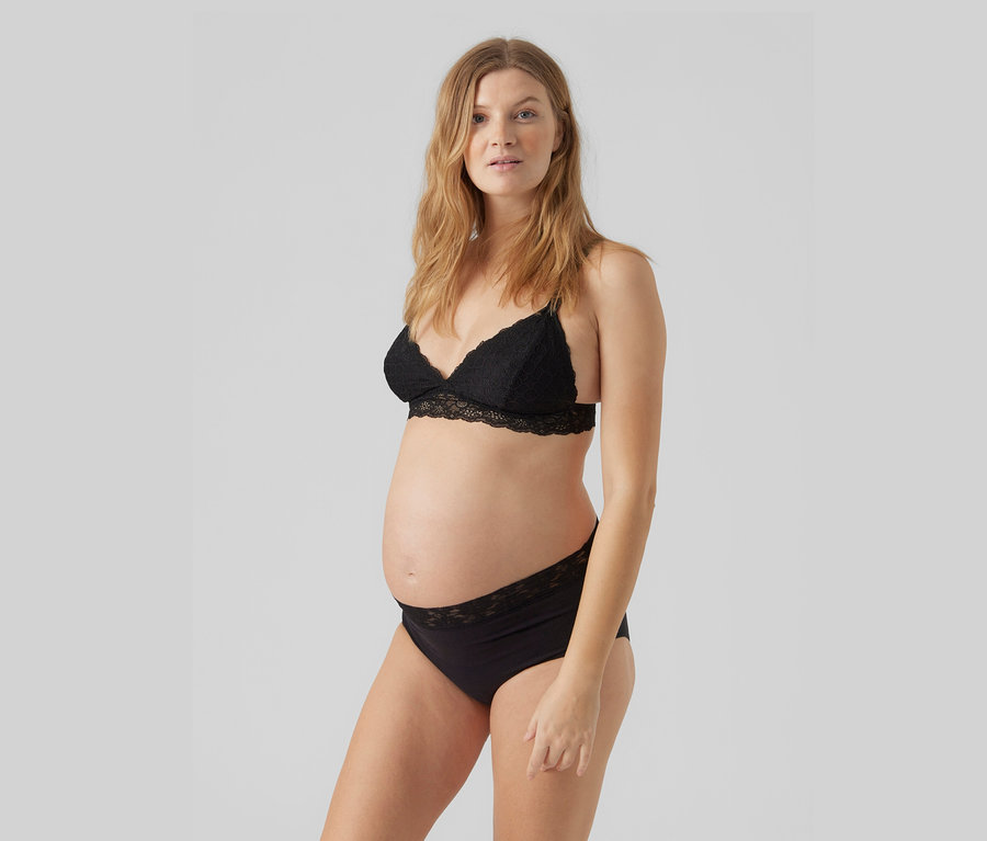 Femme enceinte aux longs cheveux blonds portant un soutien-gorge en dentelle noire et une culotte assortie.