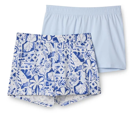 Deux shorts: un bleu clair uni et un autre blanc et bleu à motifs de coquillages et de feuilles, posés l'un sur l'autre.