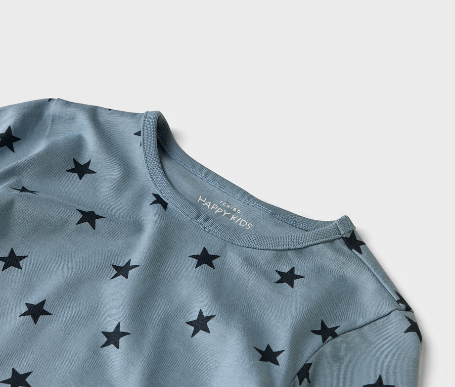 Gros plan sur un t-shirt HAPPY KIDS bleu clair avec des étoiles noires.