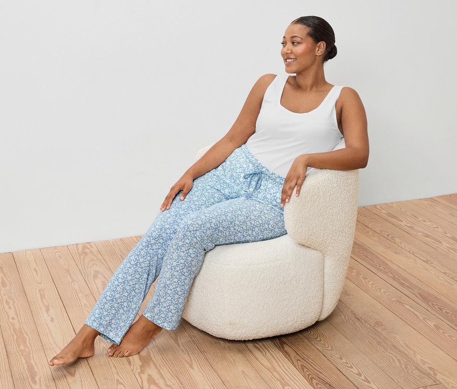 Femme assise dans un fauteuil portant une chemisette blanche et un pantalon bleu.