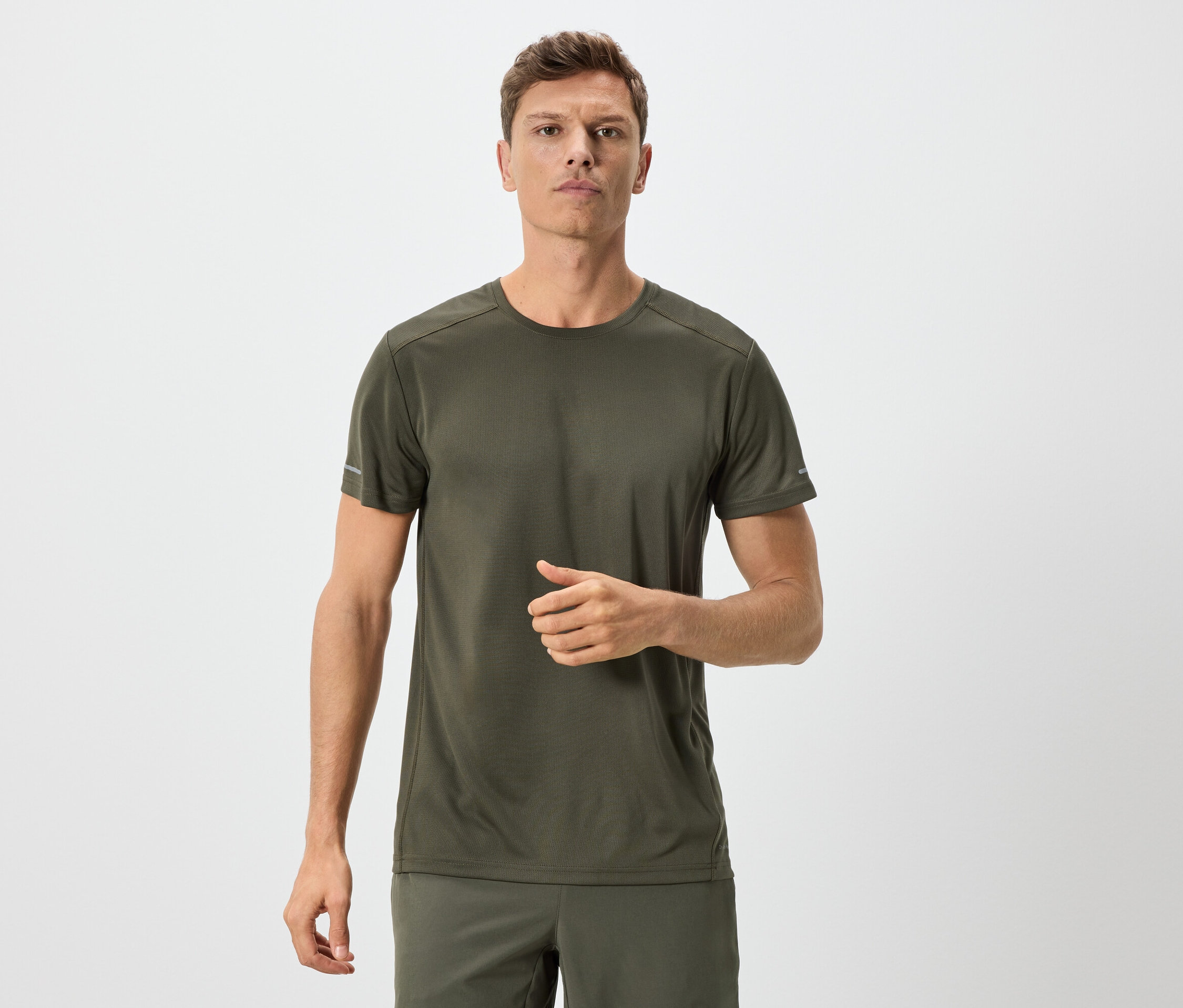 Homme en t-shirt et short vert olive sur fond neutre.