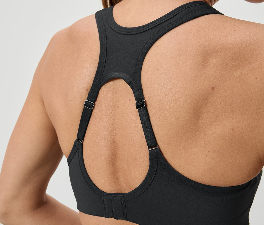 Gros plan sur le dos d'une femme portant un soutien-gorge de sport noir avec des bretelles réglables.