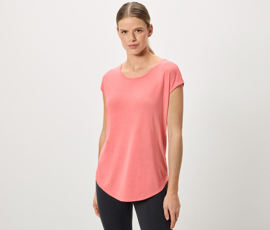 Femme avec queue de cheval portant un t-shirt corail et un legging noir.