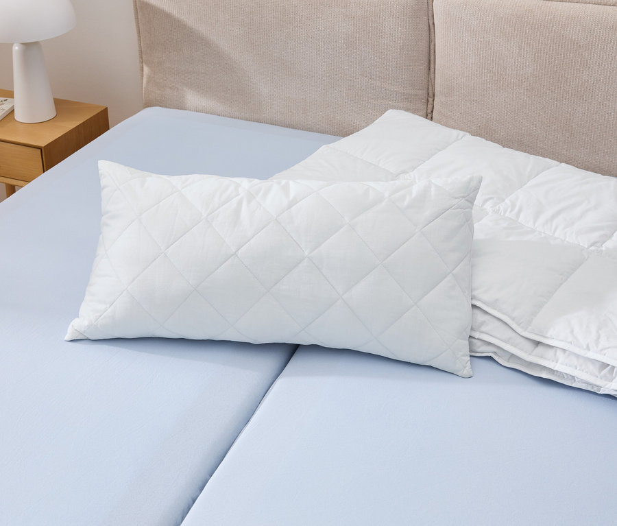 Un oreiller blanc Cell Solution®, 80 x 40 cm, est posé sur un lit bleu à côté d'une couette blanche.