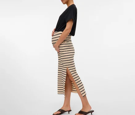 Femme enceinte portant un t-shirt noir et une jupe longue rayée MAMALICIOUS «
MLEVA » fendue avec des mules marron.