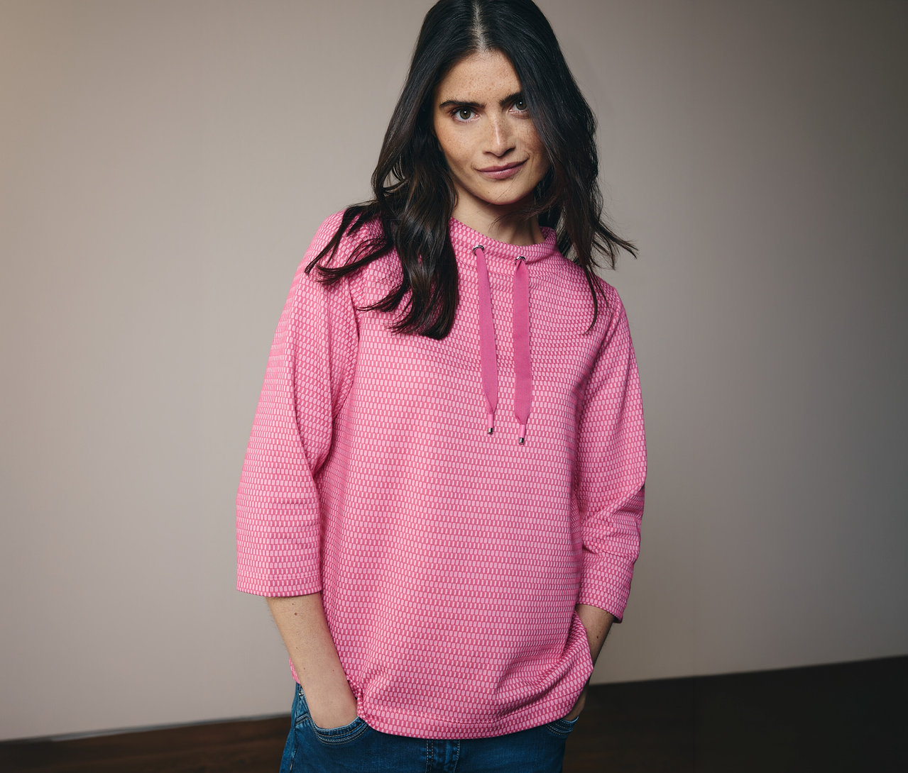 Femme portant un jean et un sweat-shirt CECIL rose à capuche avec cordon de serrage. Elle a les mains dans les poches de son pantalon.