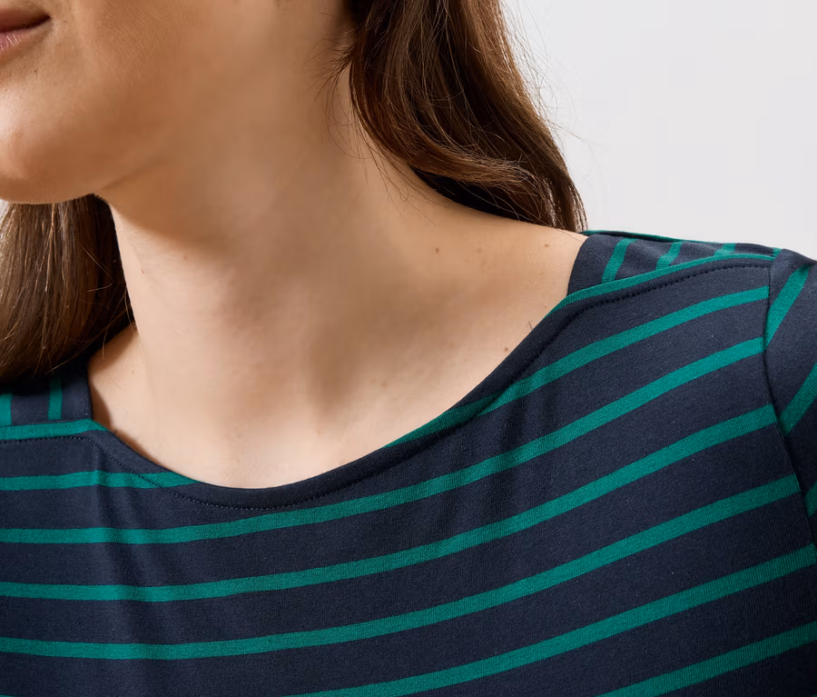 Gros plan d'une femme portant un haut rayé bleu et vert.