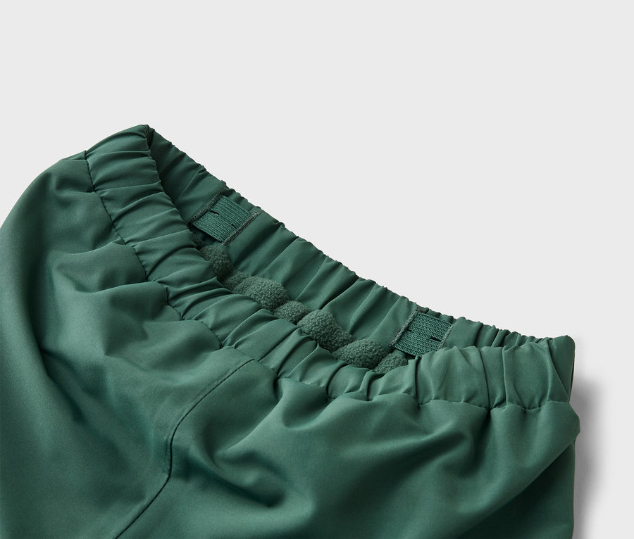 Gros plan de la taille d'un pantalon vert avec cordon de serrage et élastique.