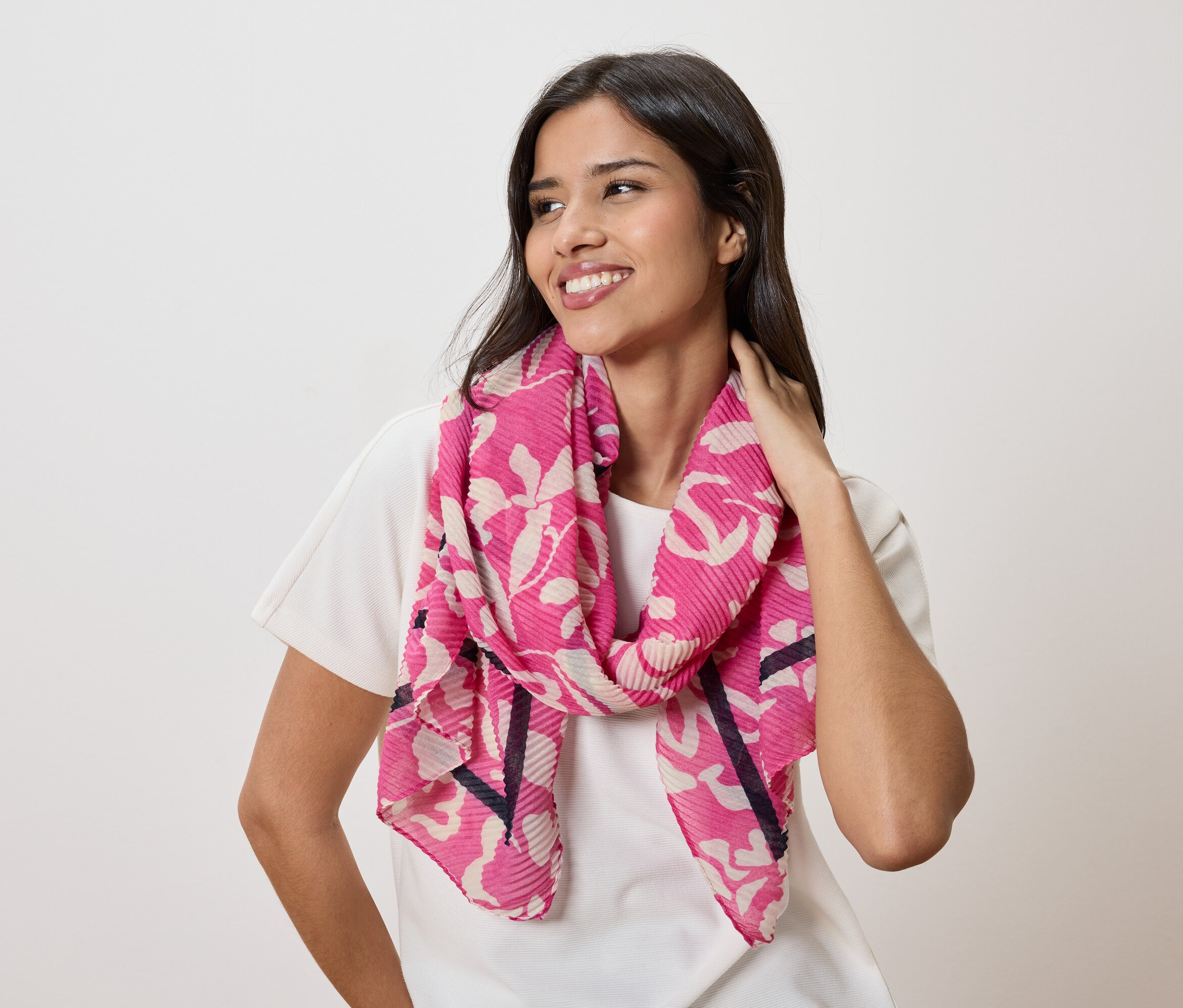 Femme portant un foulard rose à motifs floraux et un t-shirt blanc.