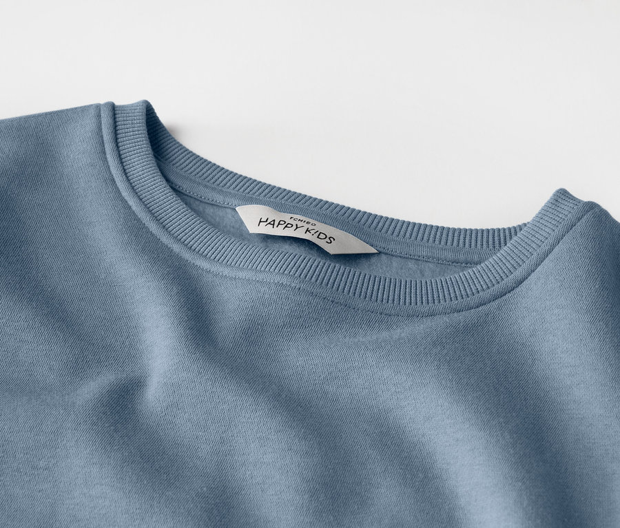 Gros plan d'un sweat-shirt bleu clair pour enfants avec une étiquette indiquant « HAPPY KIDS ».