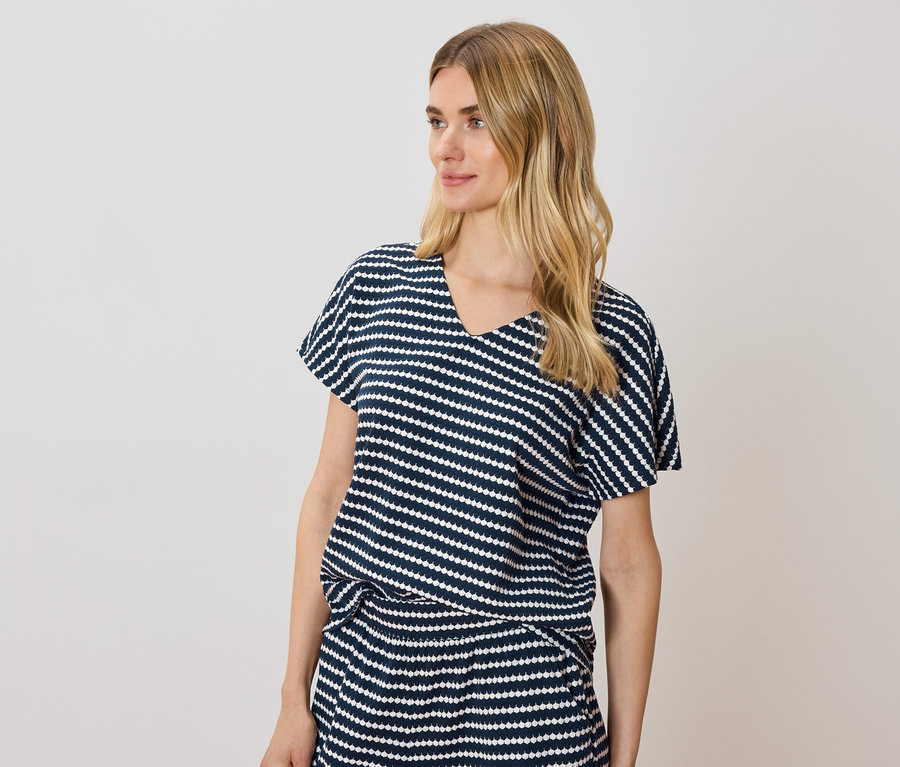 Femme blonde portant un T-shirt et une jupe rayés bleu et blanc.