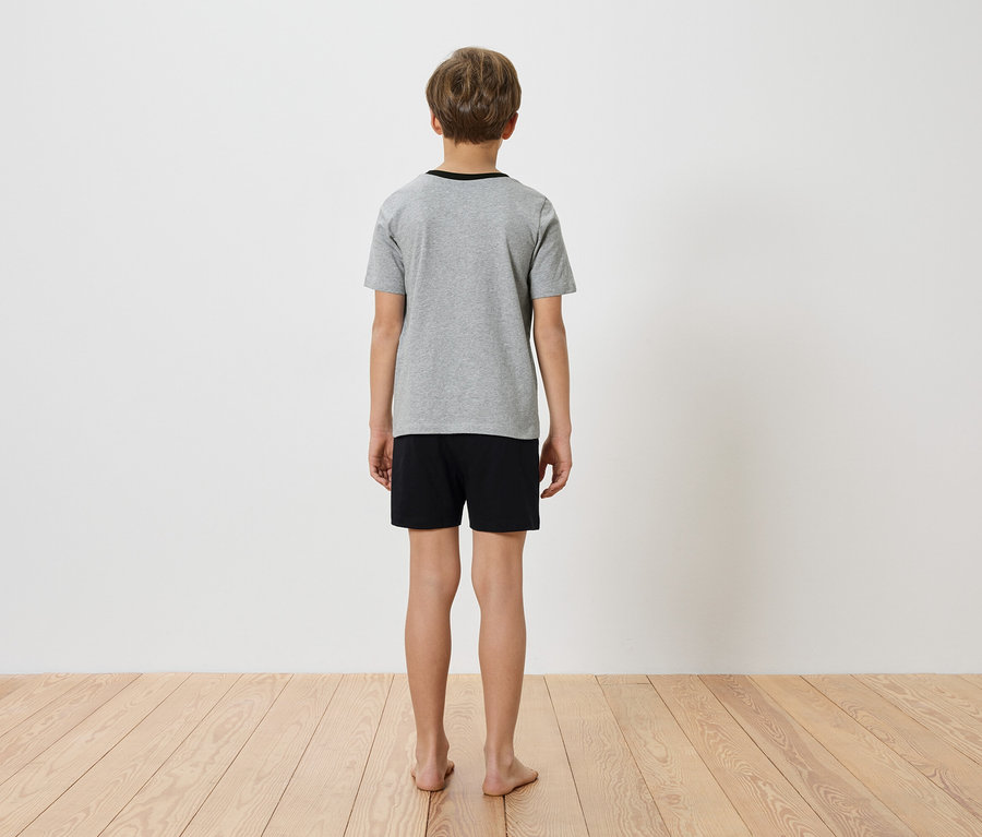 Un enfant, vu de dos, porte un t-shirt gris et un short noir.